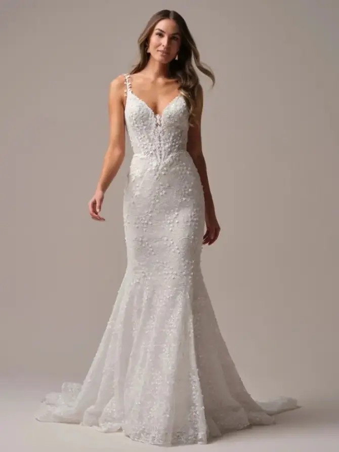 Model is wearing a mermaid wedding dress with lace motifs and a plunging neckline