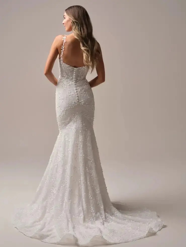 Model is wearing a mermaid wedding dress with lace motifs and a plunging neckline