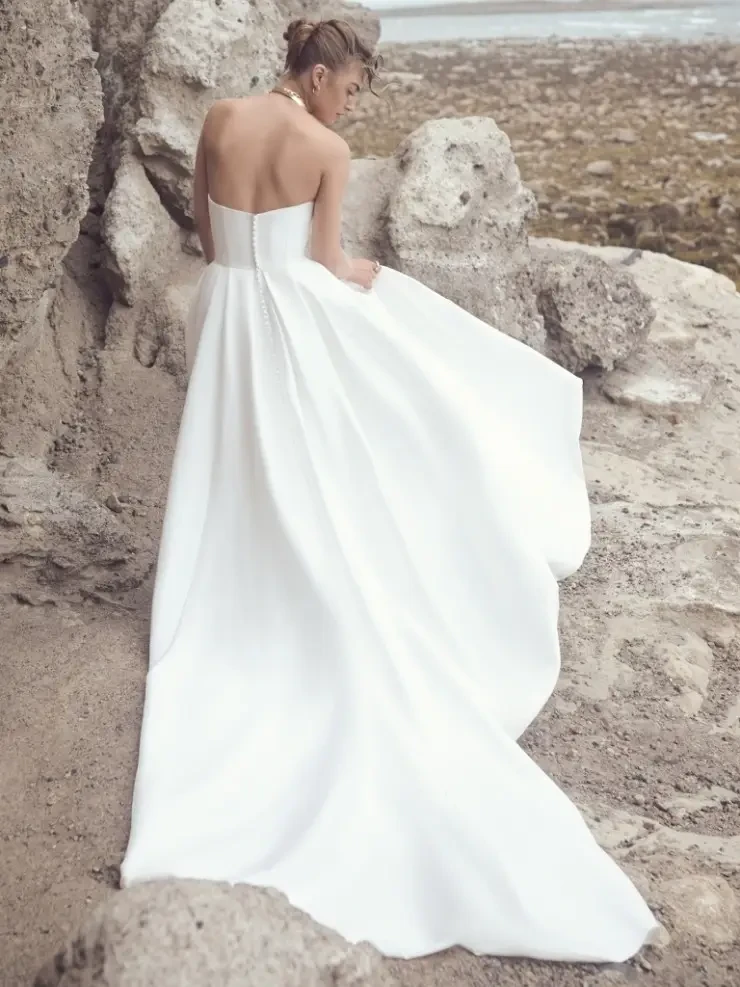Model is wearing a strapless A-line gown with a dramatic thigh-high slit.