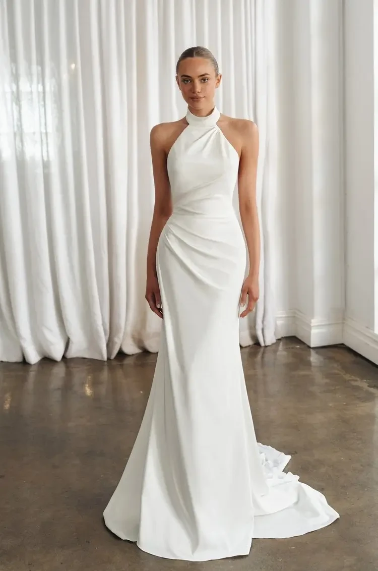 model is wearing a sleeveless high neck wedding gown