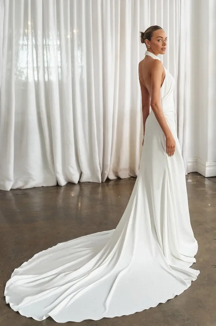 model is wearing a sleeveless high neck wedding gown