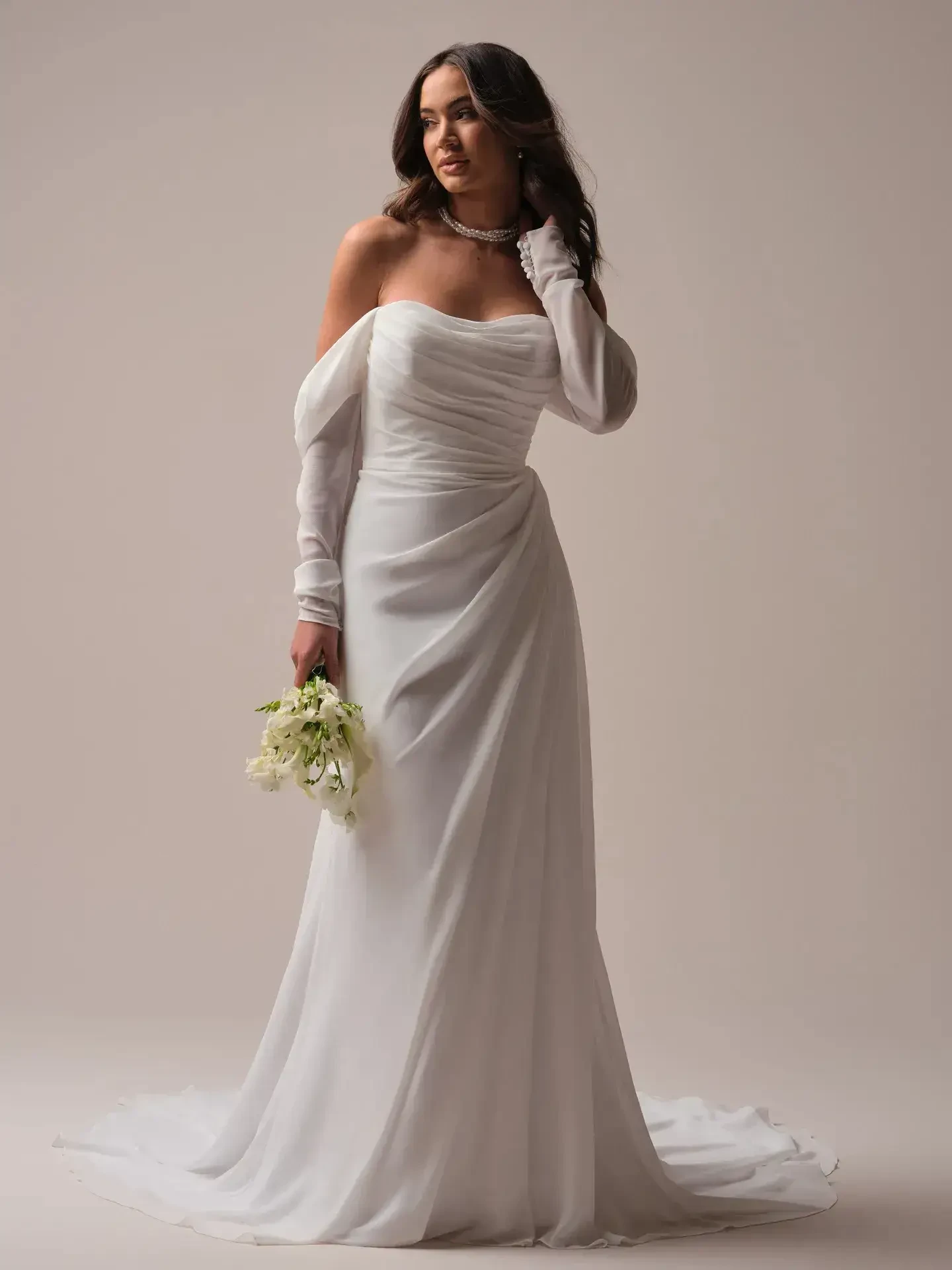 model is wearing an off the shoulder long sleeve wedding dress