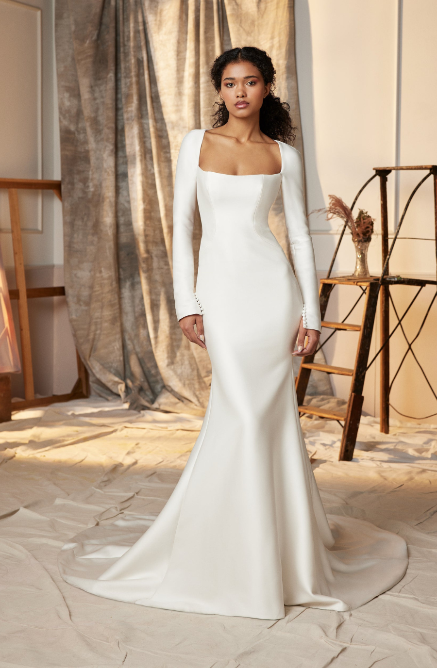 model is wearing a fit and flare long sleeve bridal gown